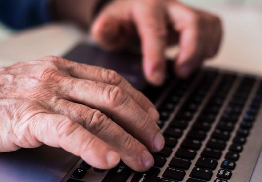 Photo of an older persons hands on a laptop keyboard 