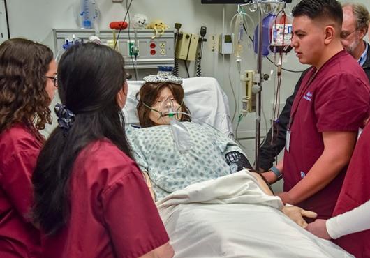 Students care for a “patient” in a MEDscience simulation. Image by Steve Lipofsky