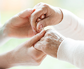 Young female physician's hands holding elderly persons hands