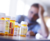 medication bottles with man out of focus in background