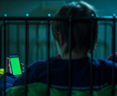teen looking at screen in bed in dark room