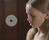Image of child playing piano with video play button overlay