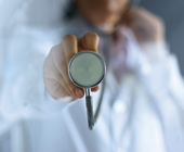 stethoscope being held to camera with doc blurred out
