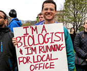 ewen-campen holding sign at rally that says "I'm a biologist and I'm running for local office."