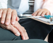Photo of doctor's hand placed reassuringly on an elderly person's hand