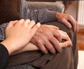 photo of hands of elderly man being held by family member