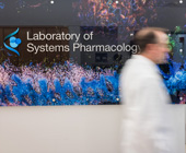 photo of researcher blurred walking by sign that says Laboratory of Systems Pharmacology