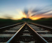 Two train tracks merge in a blurry sunset