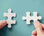 photo of person's hands putting two puzzle pieces together