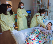 Photo of several HMS students in protective gowns examining a pediatric patient