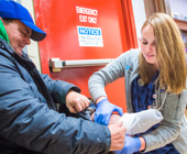Image of female student examining foot of male homeless person