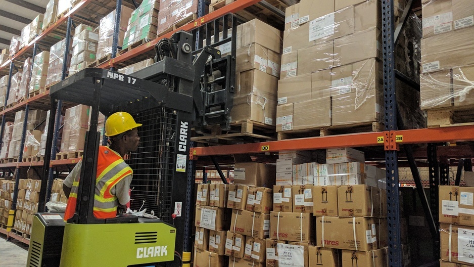 Photo of man operating a forklift loaded with boxes in a warehouse.