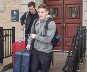 Photo of two male students with suitcases on stairs leaving Vanderbilt dorm