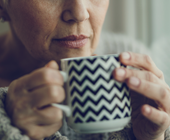 older woman holding coffee mug to face