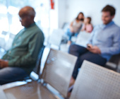 blurry photo of two men looking at phones in waiting area with two people in background