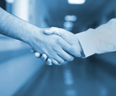 closeup photo of two male doctors shaking hand in hallway