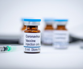 vials with COVID-19 vaccine labels and needle