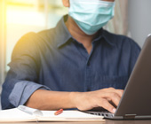 photo of person working on laptop in a mask