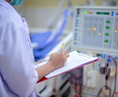 nurse with chart taking readings from kidney machine