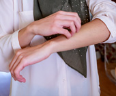 Muslim woman with 3/4 length sleeves scratching arm; image cropped to just show torso