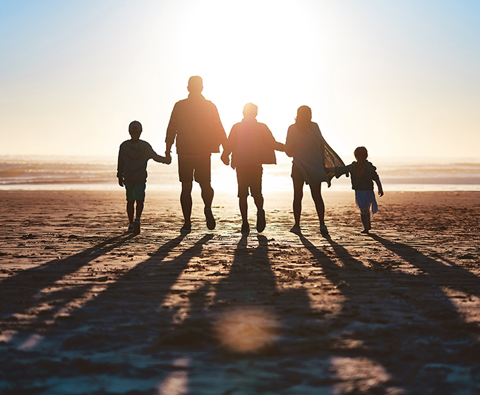 Silhouette of two adults and three children on a beach