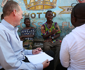 Four people having a conversation sit in front of a colorful mural