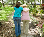 Caregiver walking with an elderly woman, photographed from behind