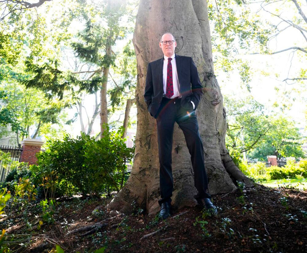 Photo of Paul Farmer standing against a big tree trunk