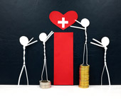 Four stick figures putting a heart with a white cross on it on a pedestal