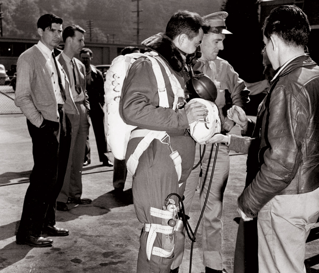 archival photo of men, some in military uniforms and one wearing face mask and other items necessary for survival during high-altitude flight