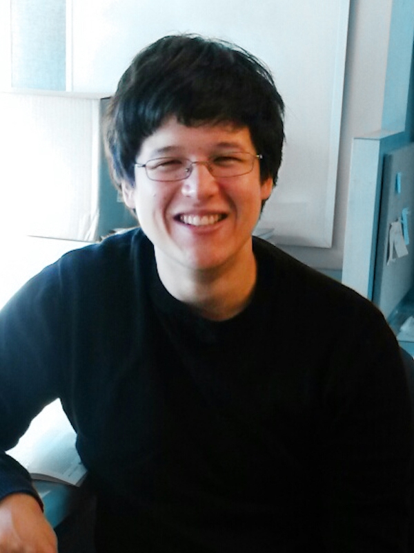 Head shot of a smiling man in glasses and sweater