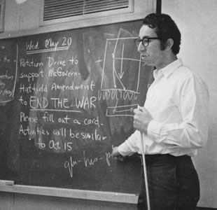 A black and white photo of a young Ed Kravitz standing at a blackboard