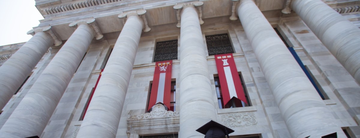 Master's students in graduation regalia in front of Gordon Hall