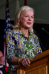 A woman standing at a podium in a patterned shirt