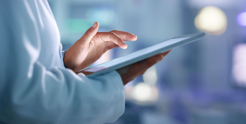 Health care professional wearing a white coat uses a tablet