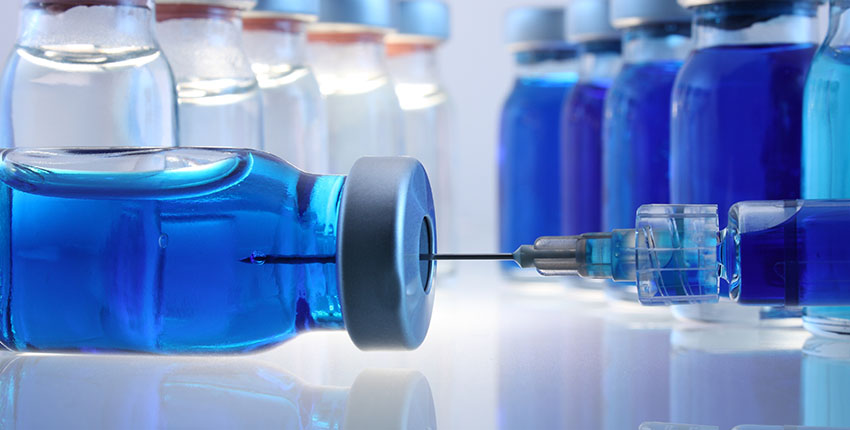 A close-up of glass containers with liquid medication and a syringe