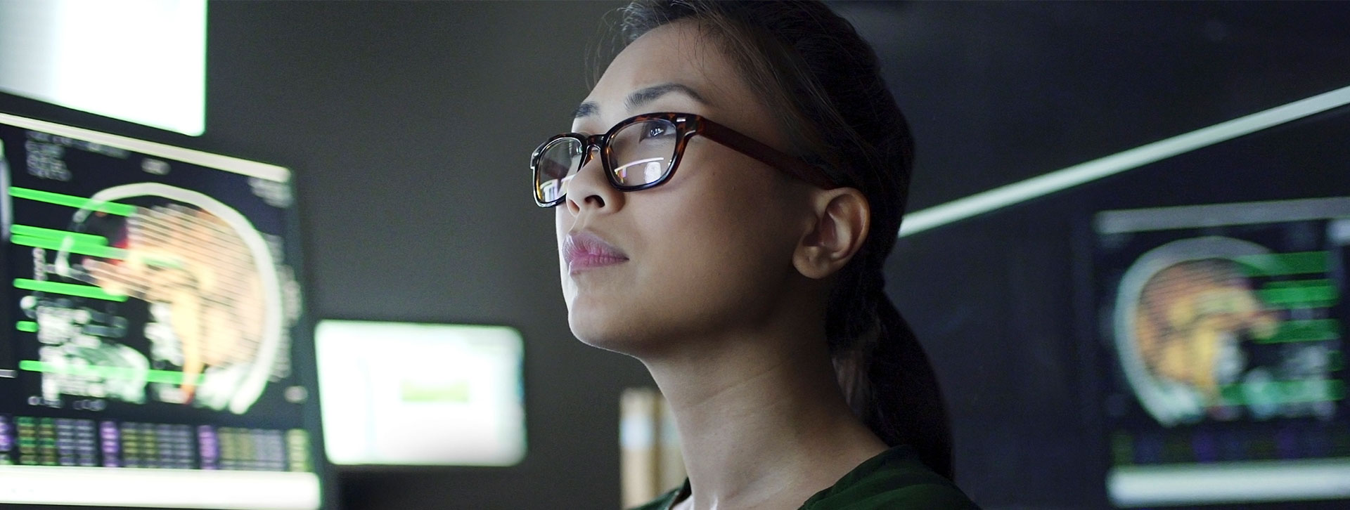 Woman with glasses analyzes scans on computer.