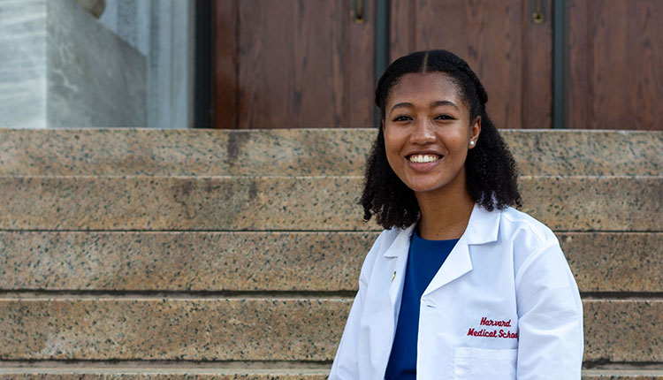 A woman in a white coat sits on stairs