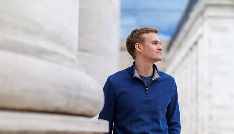 A man stands next to giant marble columns