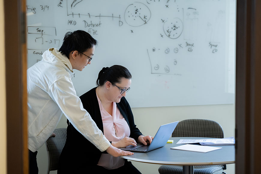 Two people collaborate at a laptop in front of a whiteboard at Harvard Medical School’s Department of Biomedical Informatics.