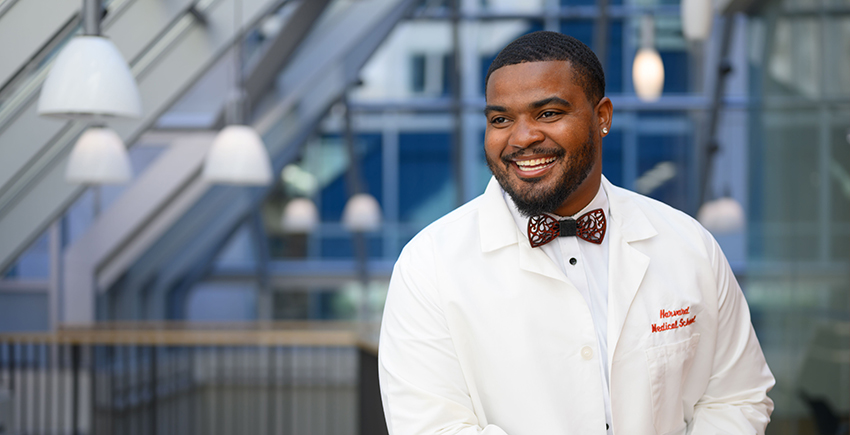 smiling young man in a bow tie and HMS white coat