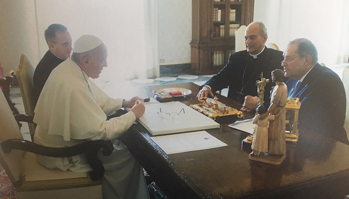 Four men sit around a desk in an office. One of them is Pope Francis.