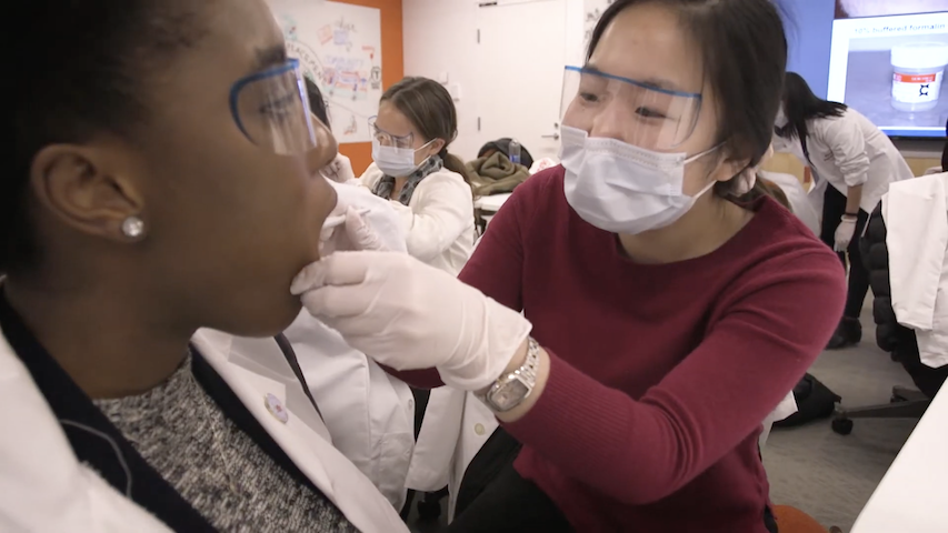 Play "Better Together: Diversity and Inclusion at HMS" video. The video thumbnail shows a medical student practicing a procedure on a patient.