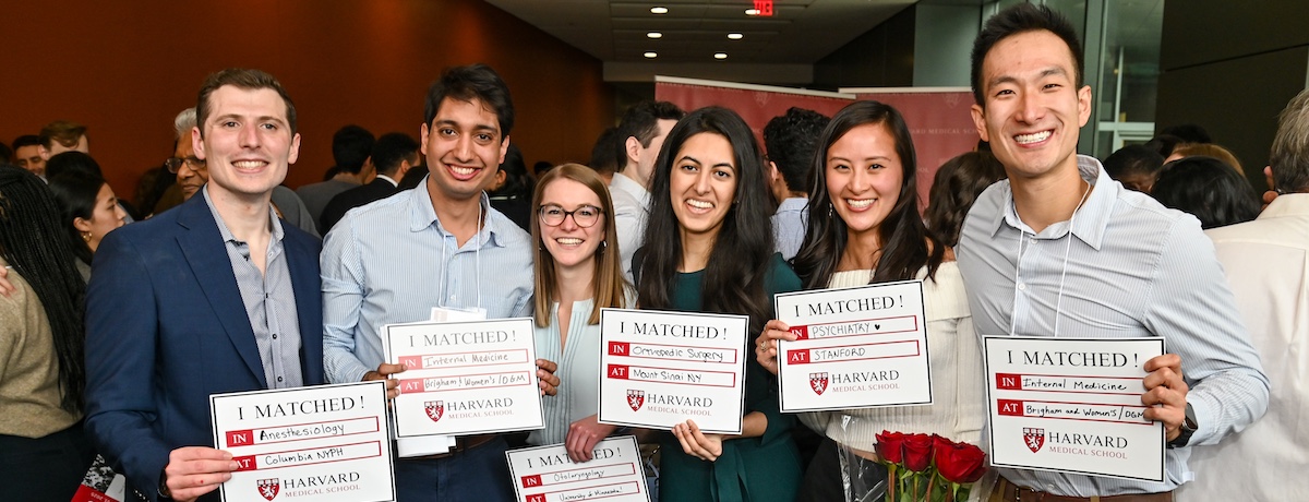 Six HMS MD students pose standing together holding signs that share where and what residency program they matched to. Image: Steve Lipofsky