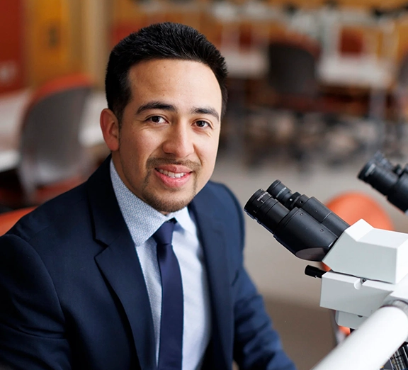 A student sitting at a microscope.