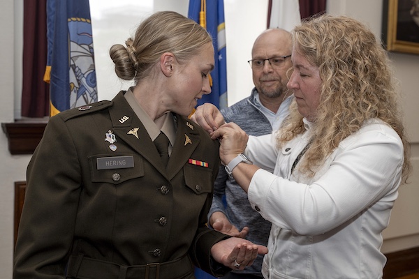 A graduating MD student watches as their parents add epaulettes to their military uniform at the recommissioning ceremony.