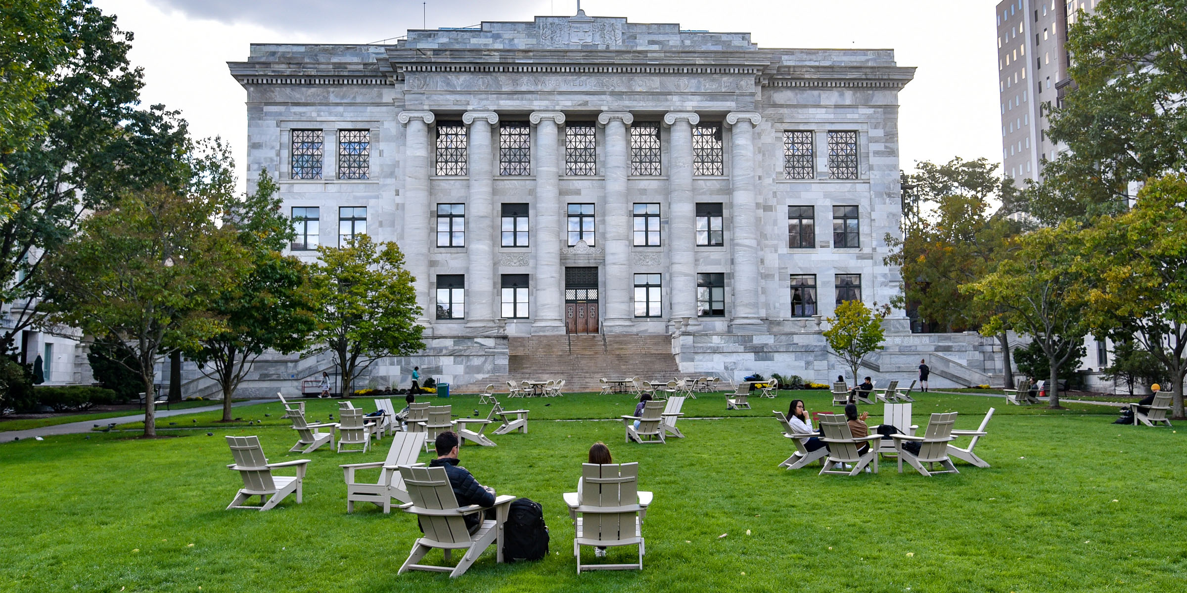People sitting in Adirondack chairs outside of Gordon Hall.