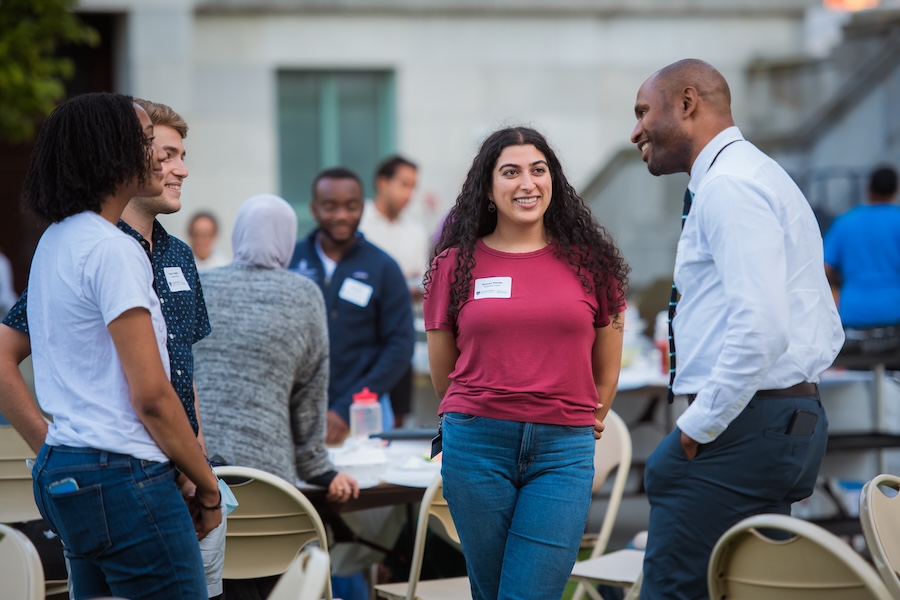 A faculty member and students engage in conversation.