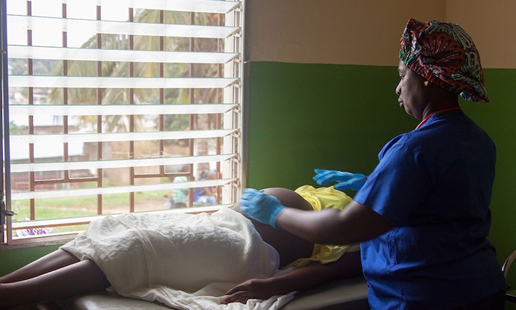 A medical provider examines a prenatal patient in a clinic room.