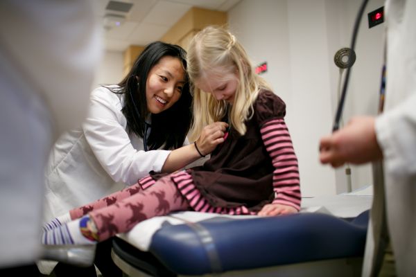 An MD student practices with a stethoscope on a pediatric patient in the Clinical Skills Center.